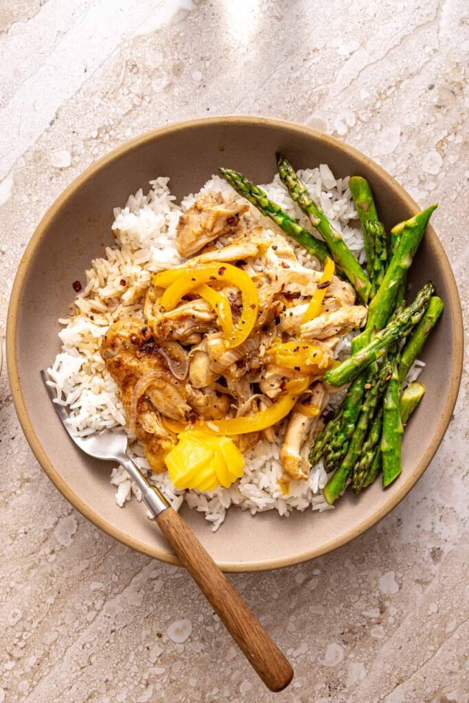 Chicken thigh rice bowl with shredded chicken, asparagus and peppers