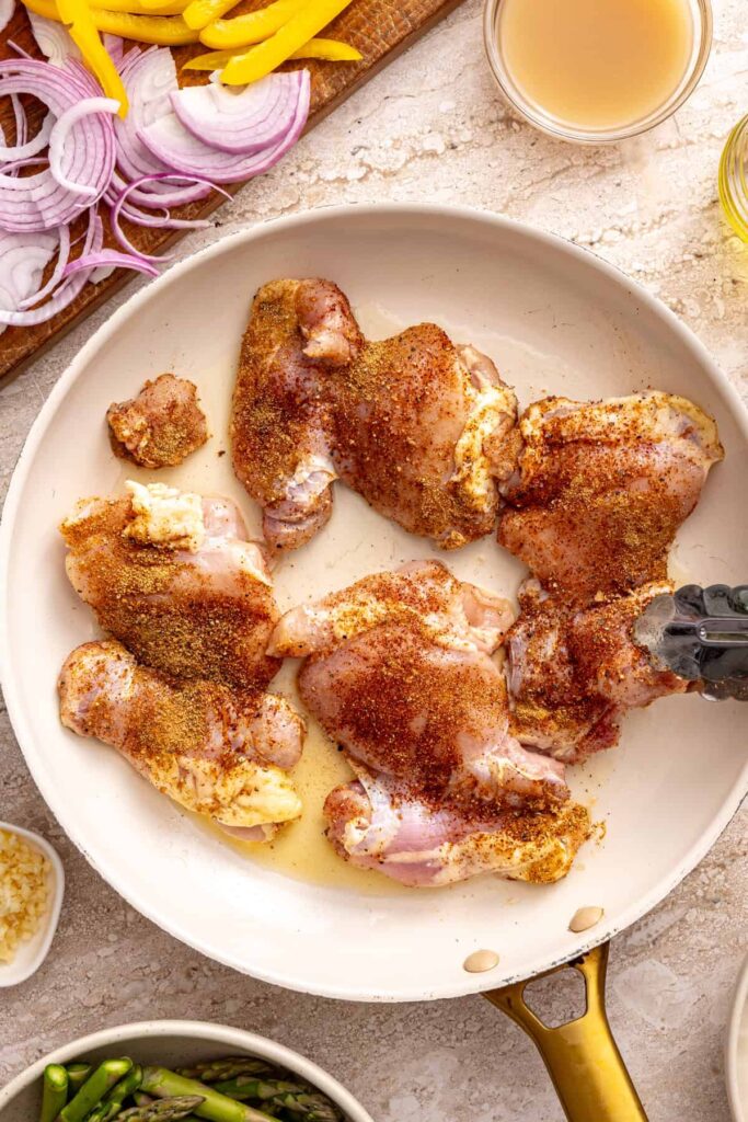 Chicken thighs cooking in pan with spices for rice bowl recipe