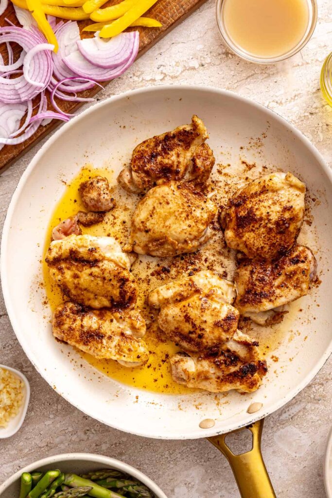 Searing chicken thighs in skillet for chicken thigh rice bowls