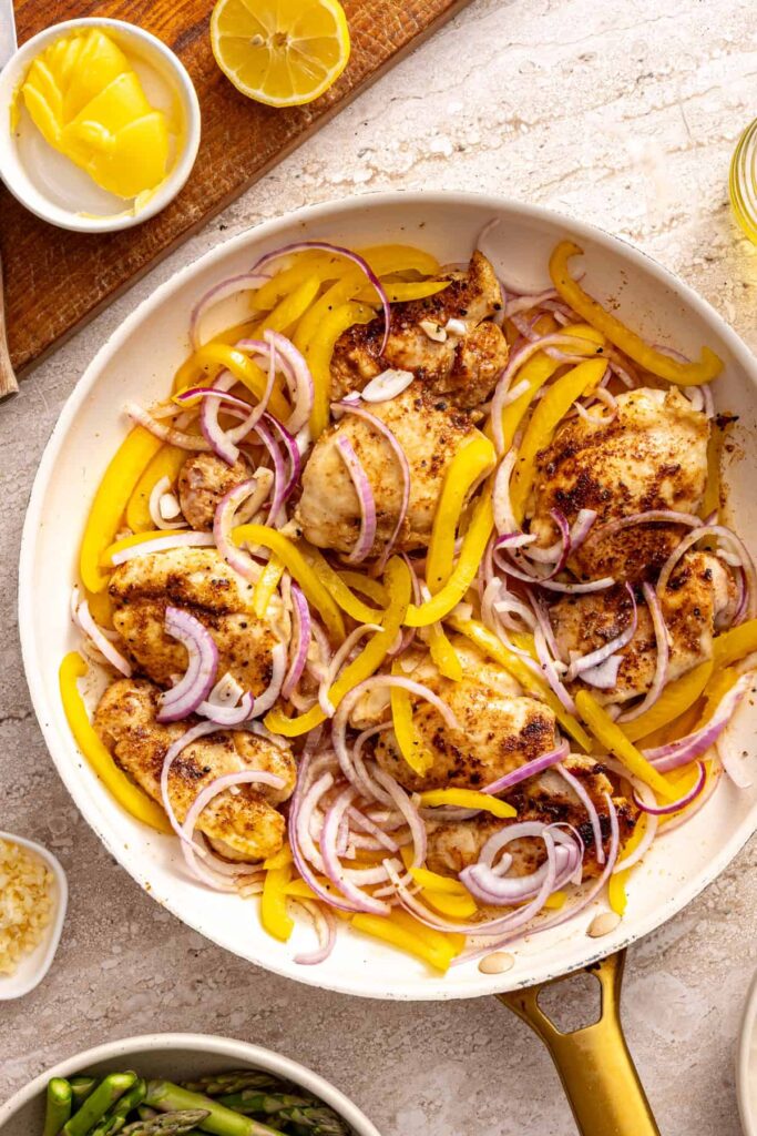 Chicken thighs cooking with peppers and onions for rice bowls