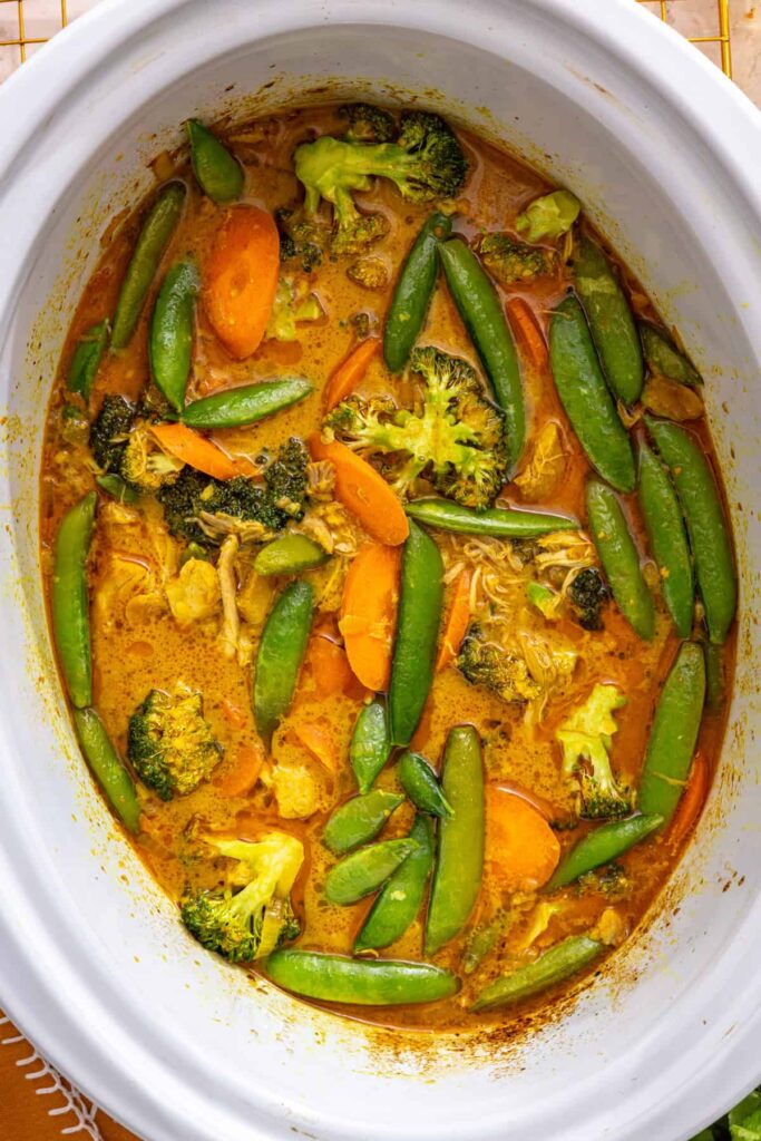 close up of finished slow cooker chicken curry with green vegetables