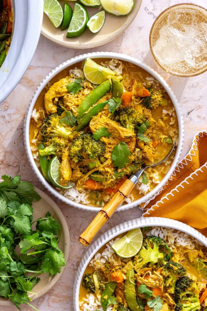 crockpot chicken curry bowl with spoon, napkins, and lime wedges