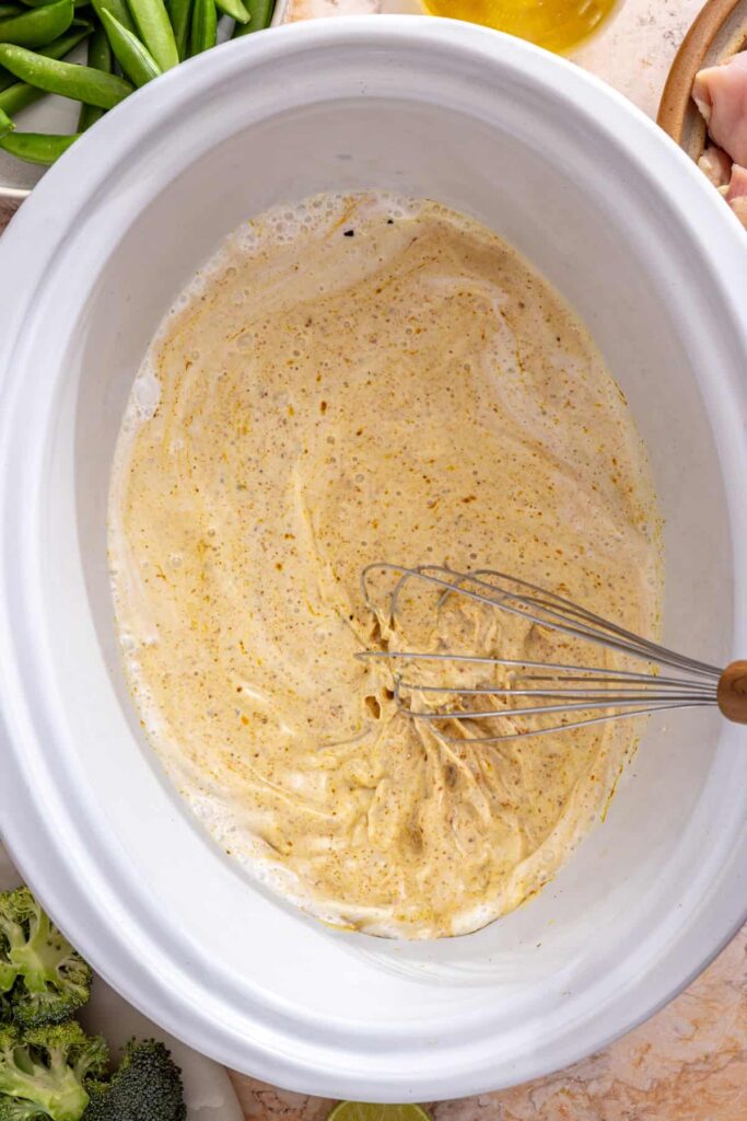 coconut milk and broth whisked with curry paste in slow cooker