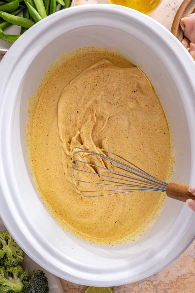 mixing curry paste, coconut milk, and broth in crockpot chicken curry