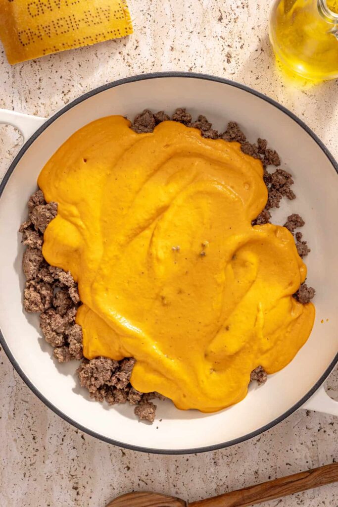 Butternut squash sauce mixed with ground beef in skillet