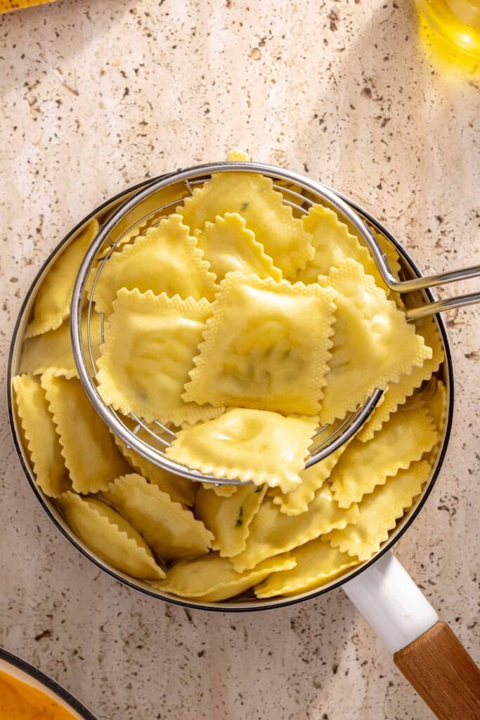 Boiling gluten-free ravioli for creamy veggie pasta