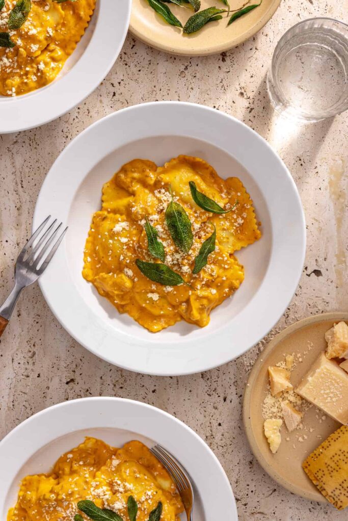 zoomed out overhead view of raviolis with creamy veggie sauce on a styled table