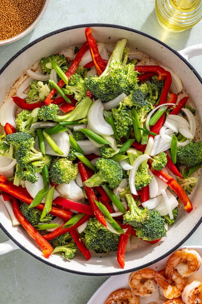 Vegetables sautéing in skillet for shrimp stir fry with broccoli, peppers, and onions
