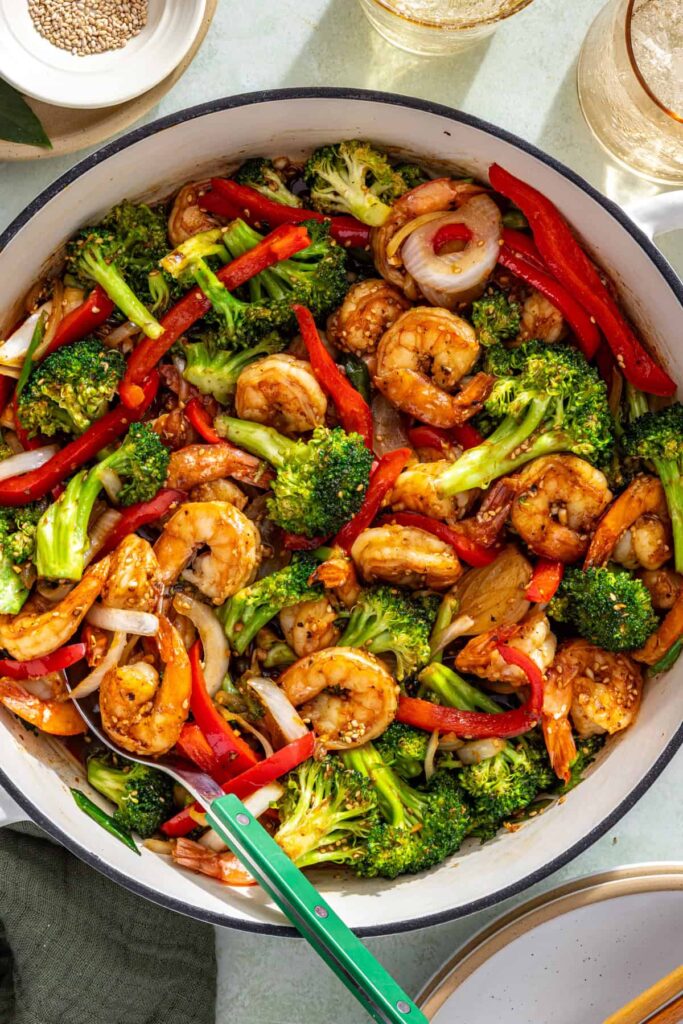 Shrimp stir fry finishing in pan as sauce thickens and coats ingredients