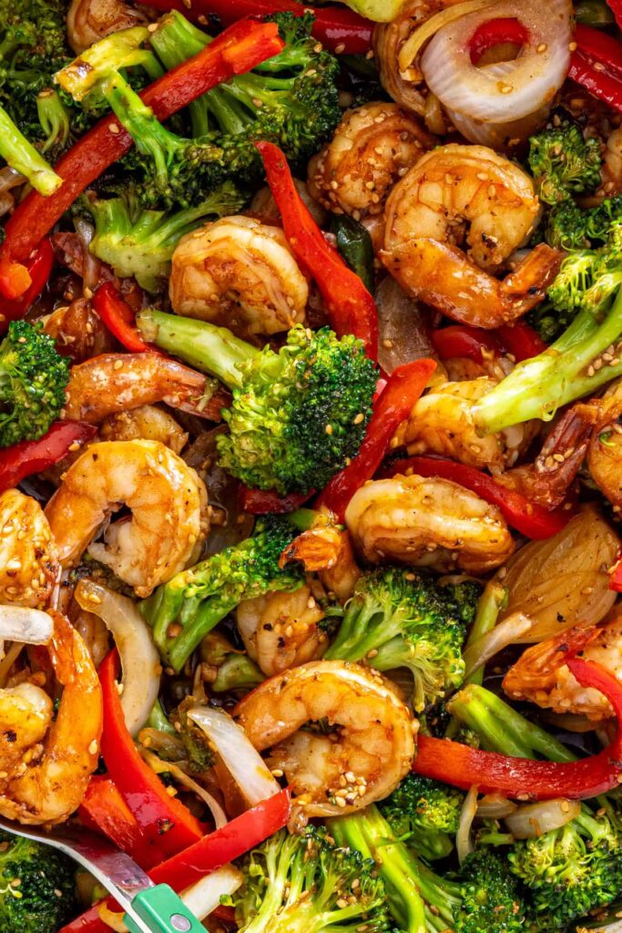 Detailed view of shrimp stir fry with glossy sauce and sesame seeds