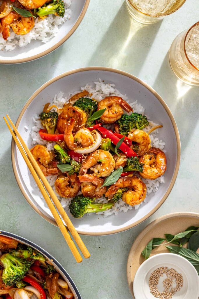 overhead view of easy shrimp stir fry served over rice in a bowl with chopsticks