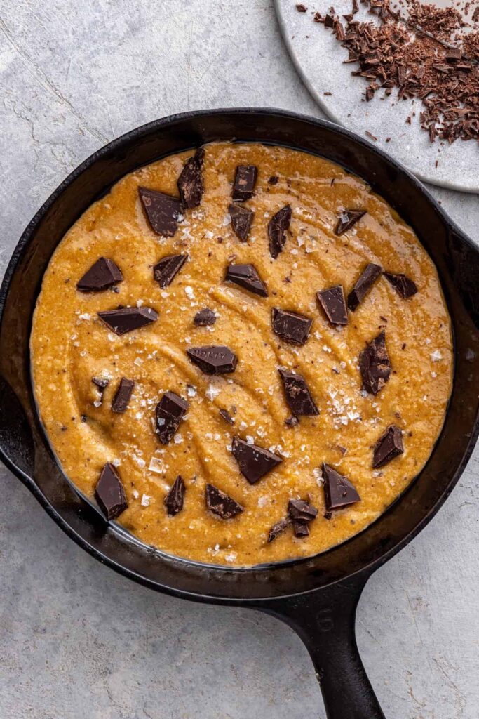 Unbaked gluten-free cookie skillet topped with chocolate and flaky salt