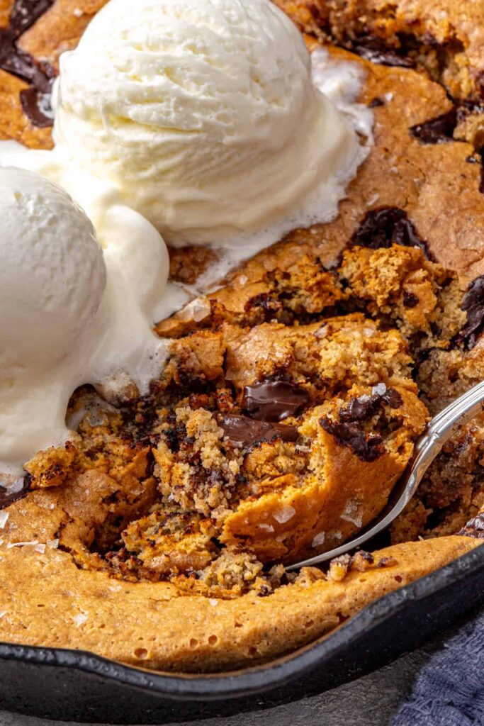 close-up shot of Healthy pizookie-style cookie skillet with soft baked center and ice cream on top