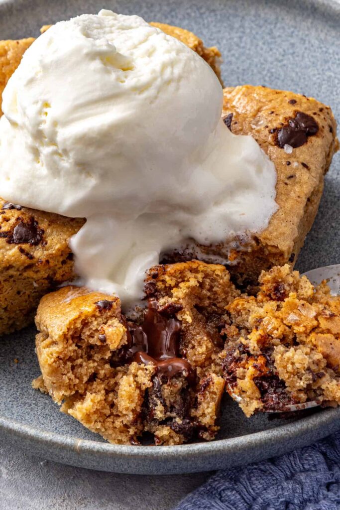 close-up of gooey gluten-free chocolate chip cookie skillet individual serving on a plate with ice cream