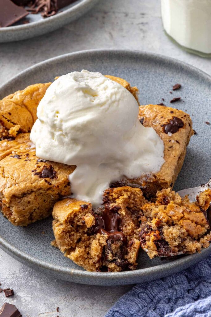 Gooey dairy-free cookie skillet dessert plated with spoon on a styled table