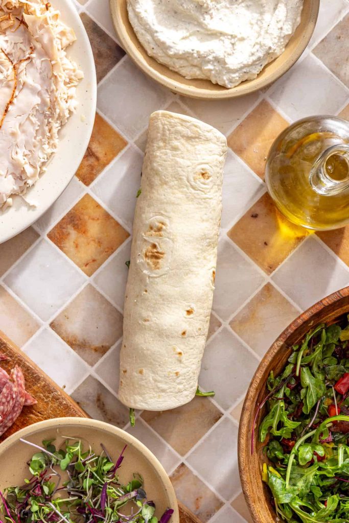 Rolling tortilla tightly into a turkey wrap log