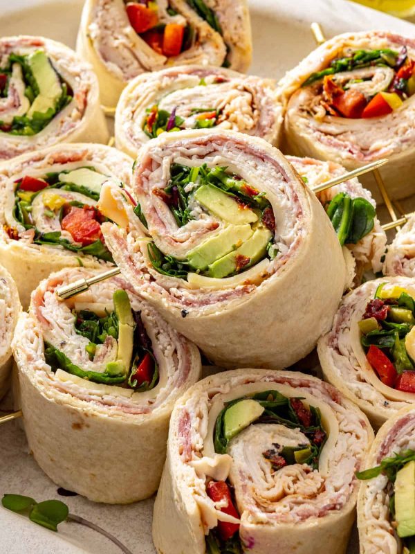 High-protein turkey pinwheels with cottage cheese spread, turkey, salami, avocado, and greens on a serving platter