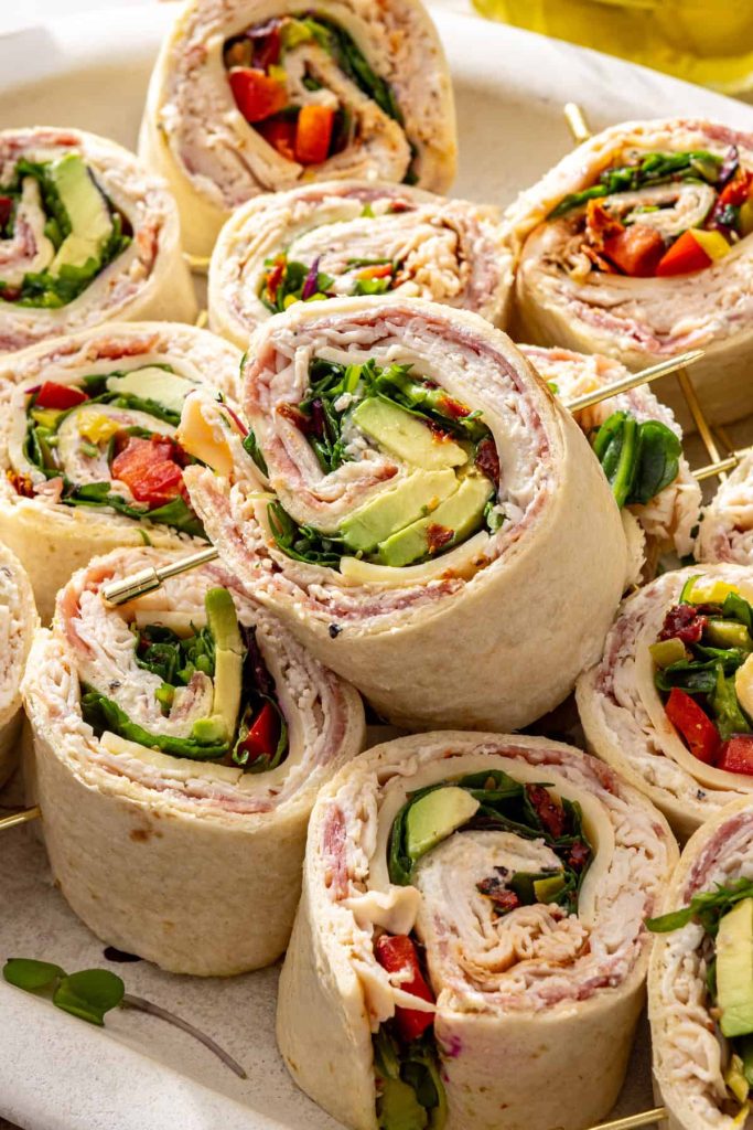 High-protein turkey pinwheels with cottage cheese spread, turkey, salami, avocado, and greens on a serving platter