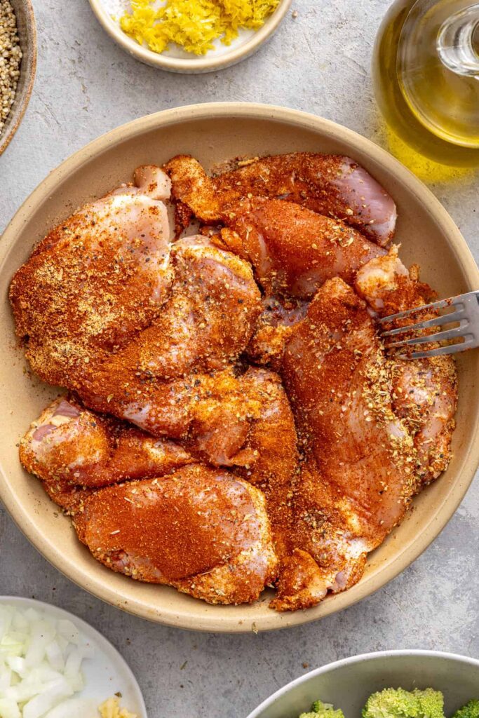 Seasoned chicken thighs prepared for lemon herb chicken quinoa pilaf