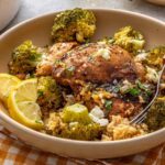 Lemon herb chicken quinoa pilaf served in a shallow bowl with lemon wedges and a fork on a styled table