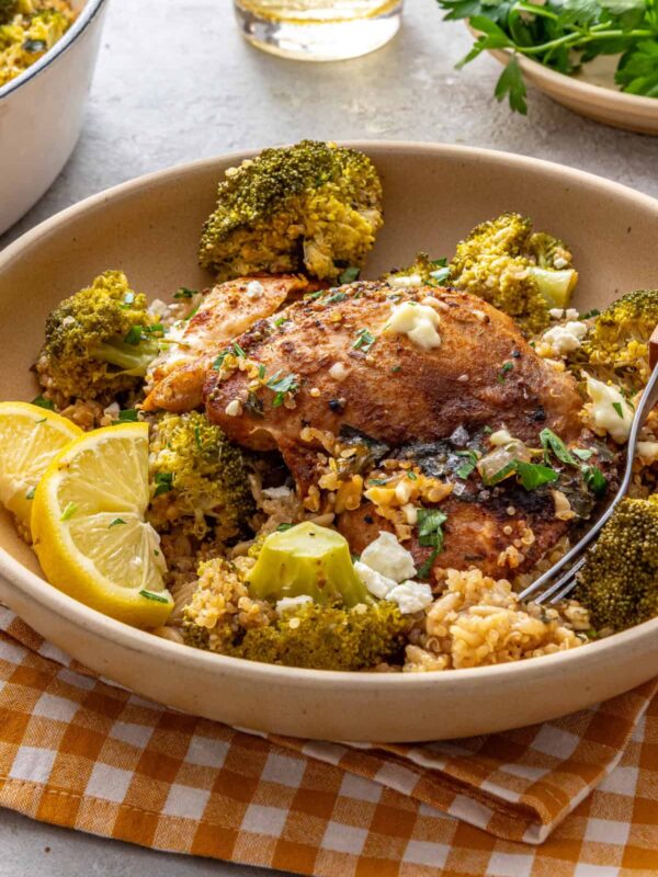 Lemon herb chicken quinoa pilaf served in a shallow bowl with lemon wedges and a fork on a styled table