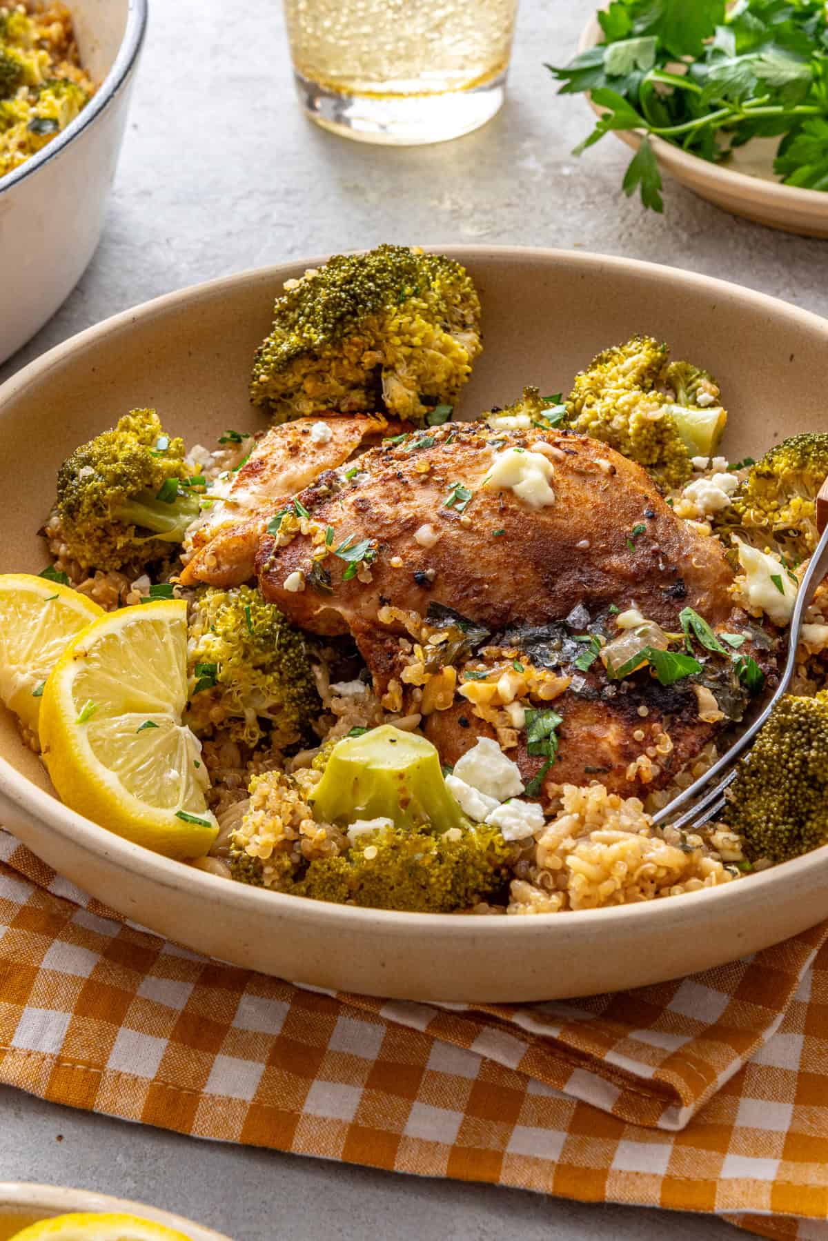Lemon herb chicken quinoa pilaf served in a shallow bowl with lemon wedges and a fork on a styled table