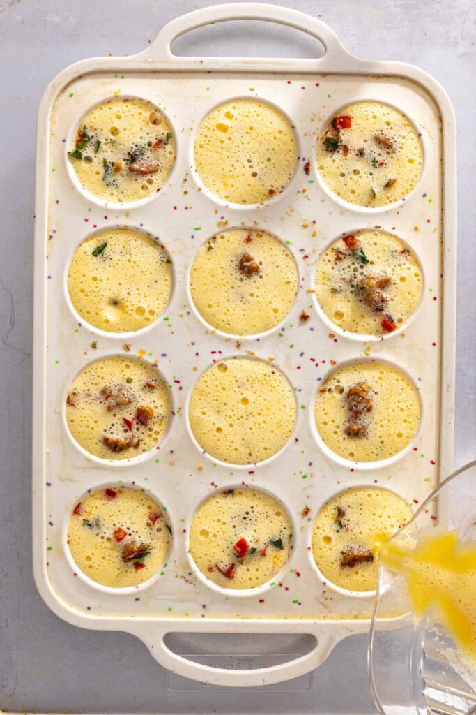Pouring fluffy egg mixture into prepared potato crust cups for gluten-free quiche cups