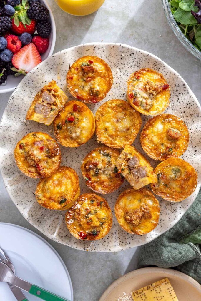 Overhead styled shot of gluten-free quiche cups served on a cake stand with berries and orange juice