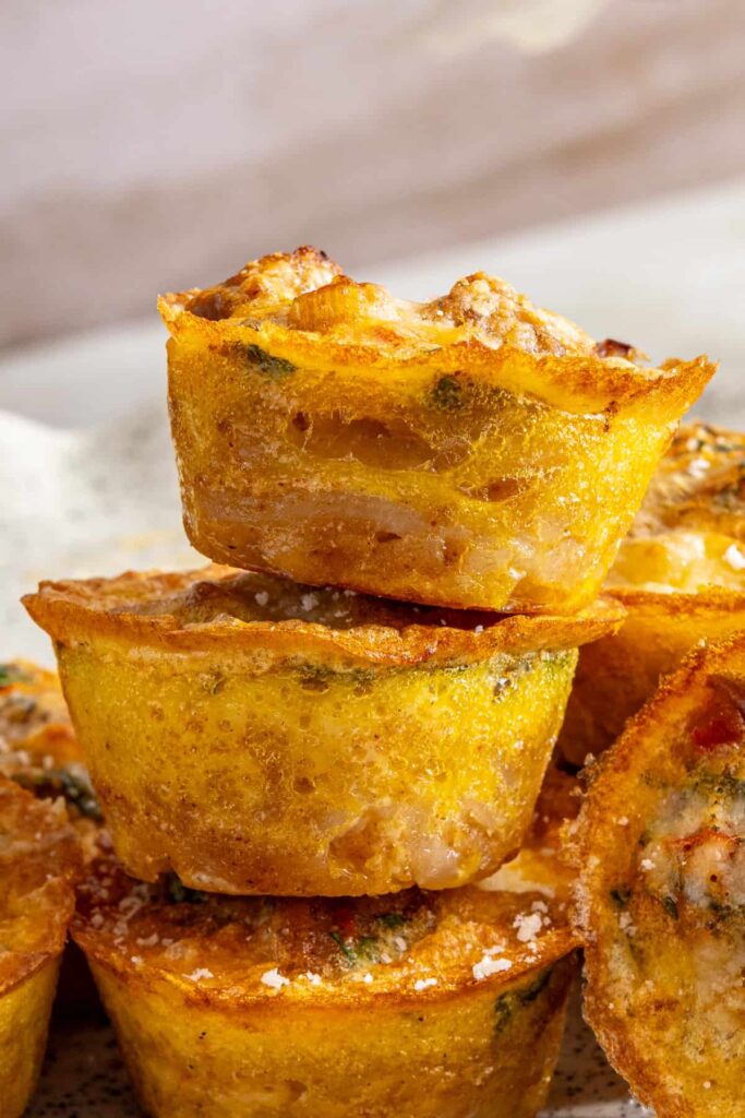 Stacked mini quiche cups highlighting layers of potato crust and egg filling