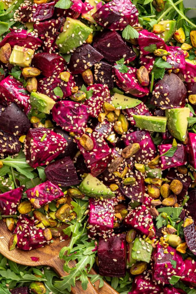 close-up texture shot of beet salad with goat cheese, avocados, sesame seeds and tahini dressing