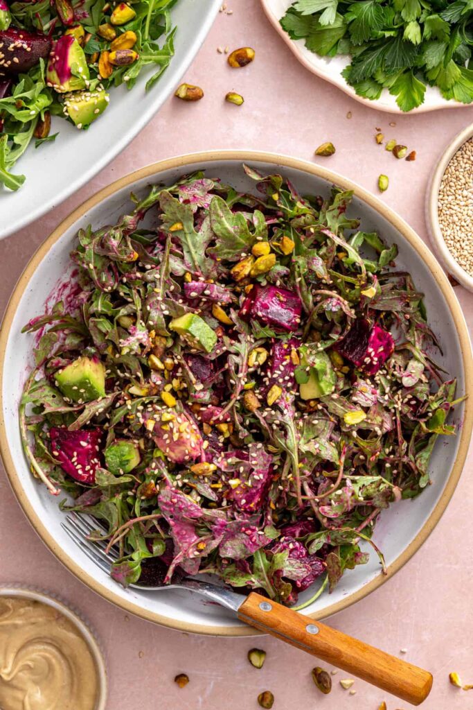 Tossed roasted beet salad served in a bowl with a fork