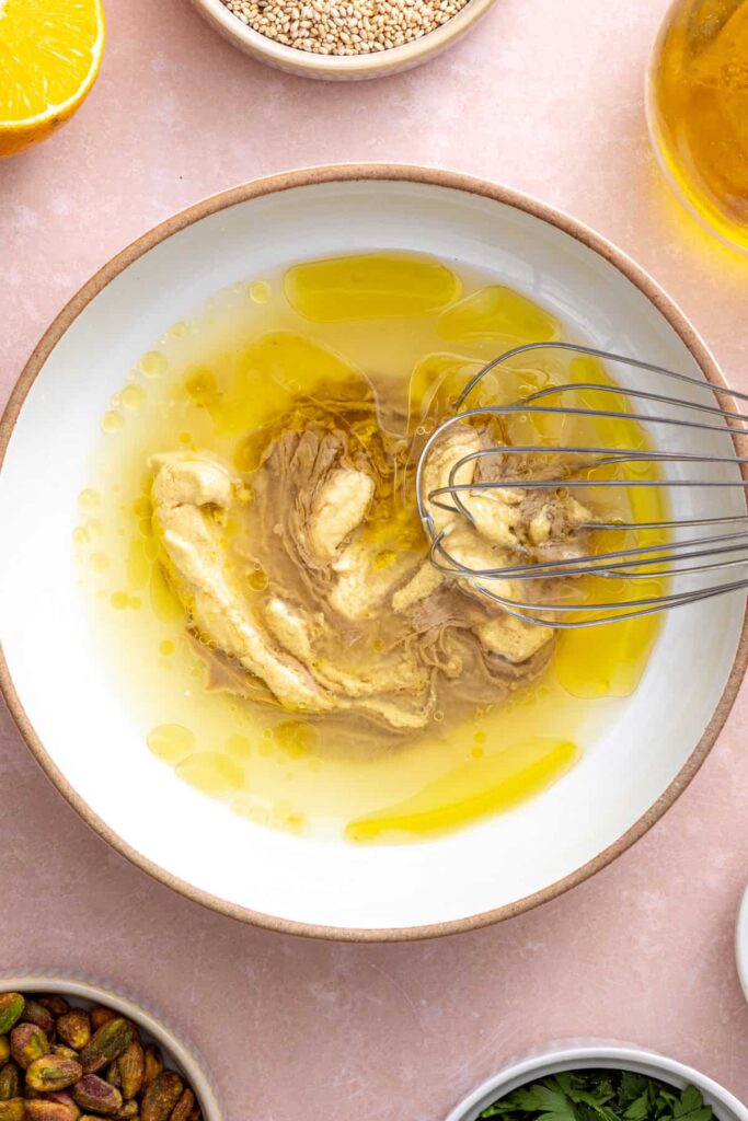 Tahini dressing being whisked in a large bowl