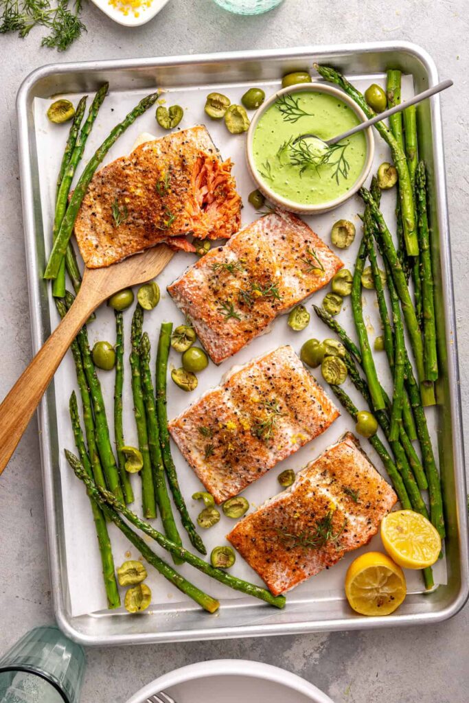 Overhead shot of sheet pan salmon and asparagus bowls on a styled dinner table