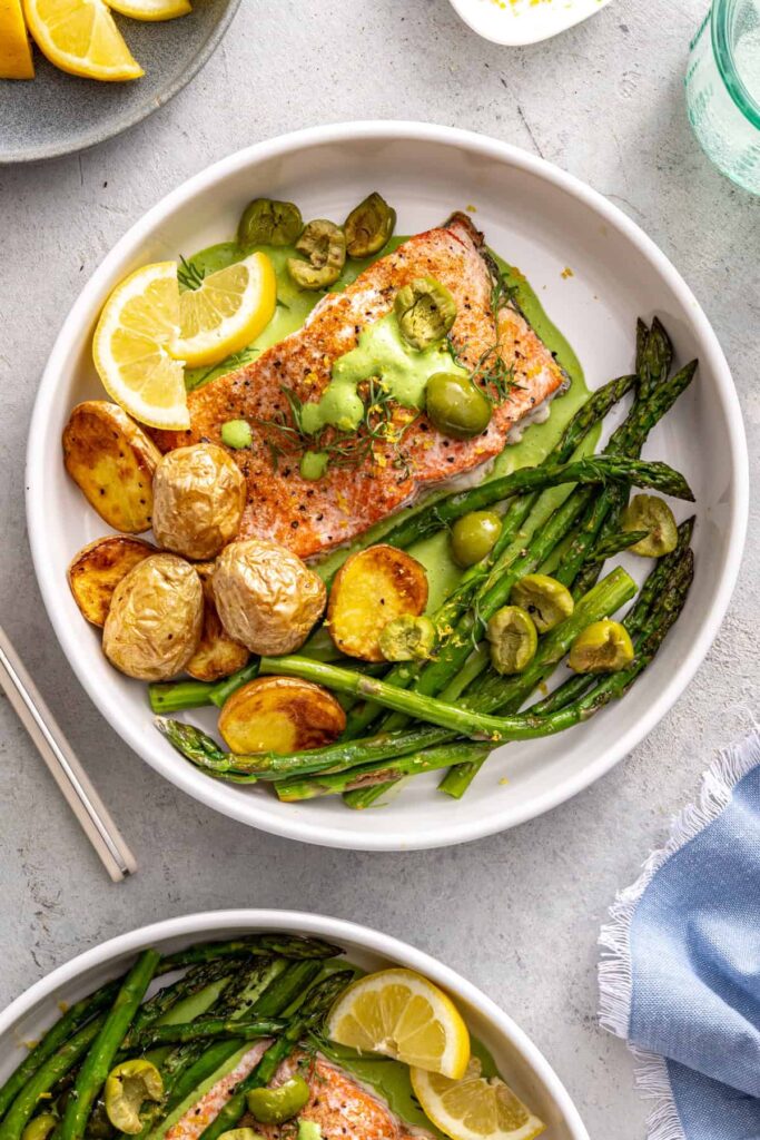 Healthy salmon and asparagus dinner bowl with lemon wedges and potatoes