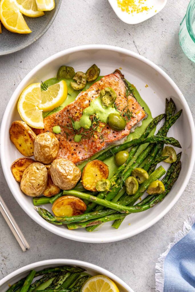 Sheet pan salmon and asparagus bowl with olives, herbs, and creamy sauce