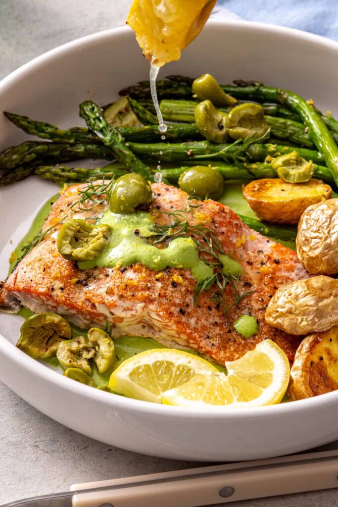 Lemon squeezed over salmon fillets and roasted asparagus