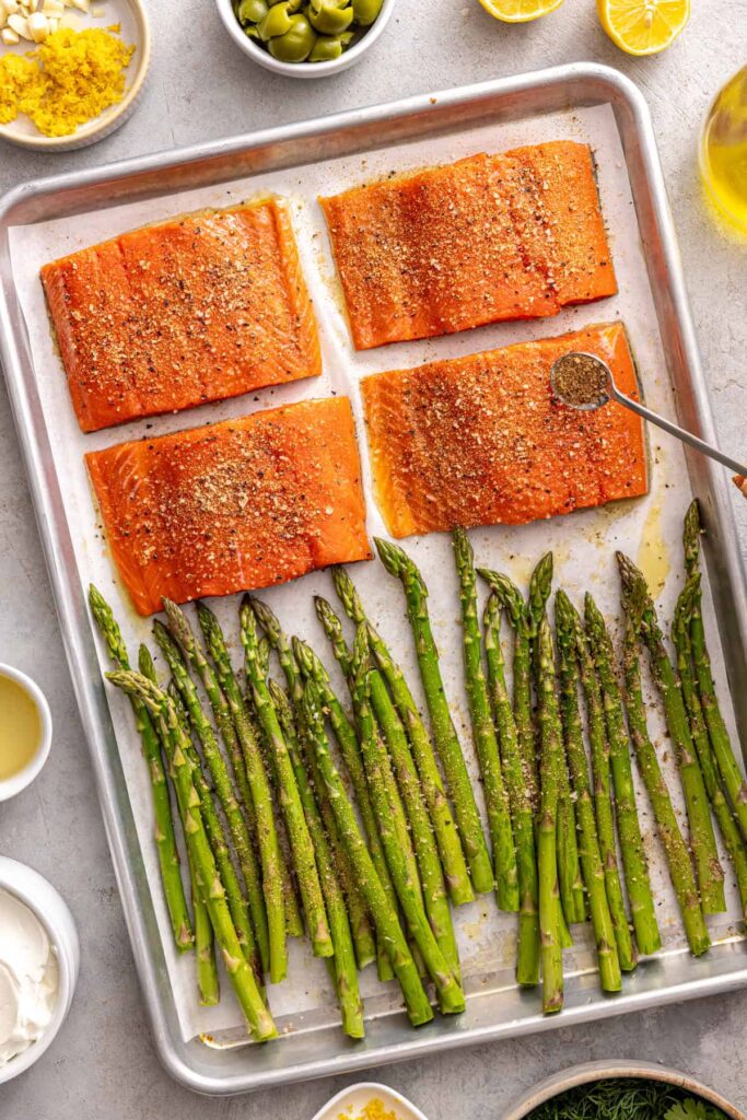 Preparing baked salmon and asparagus with olive oil and spices