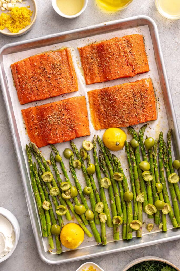 Seasoned salmon fillets and asparagus ready to bake