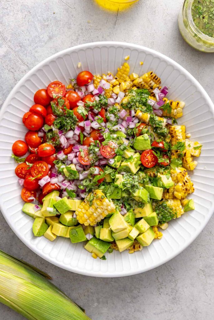 Building a grilled corn salad with tomatoes and avocado
