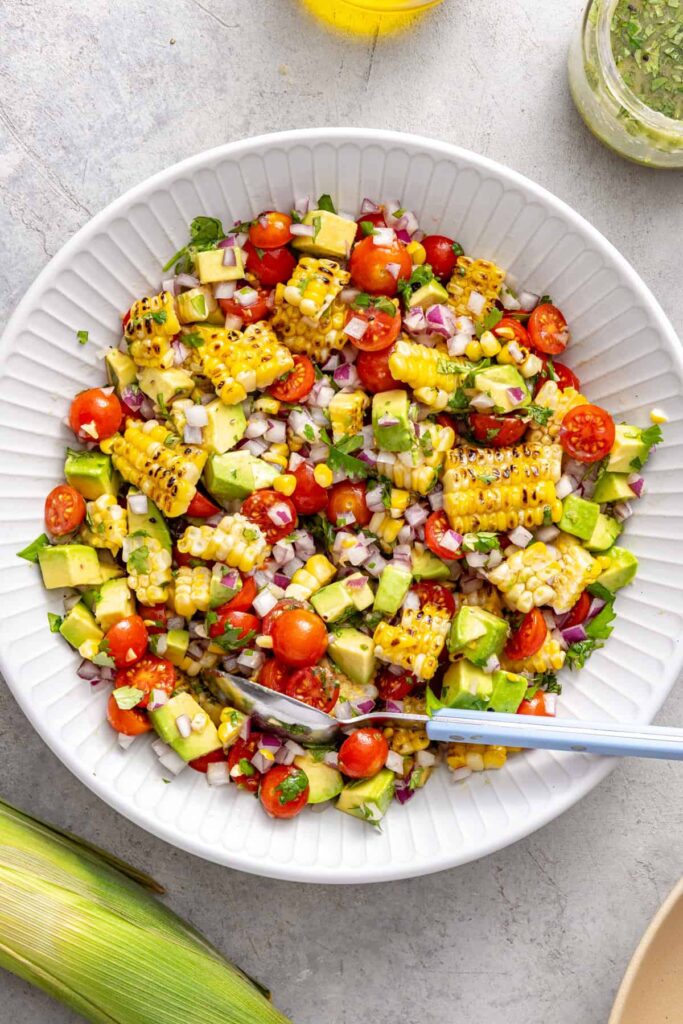 Tossing corn and tomato salad with cilantro lime dressing