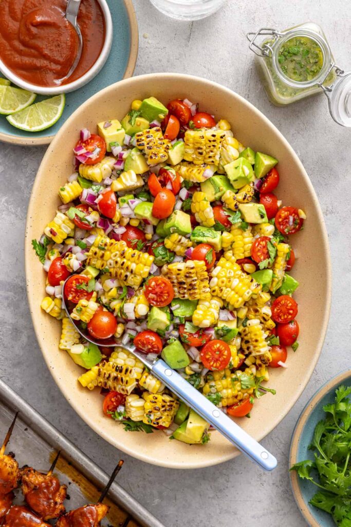 Corn and tomato summer salad served in an oval bowl on a colorful table