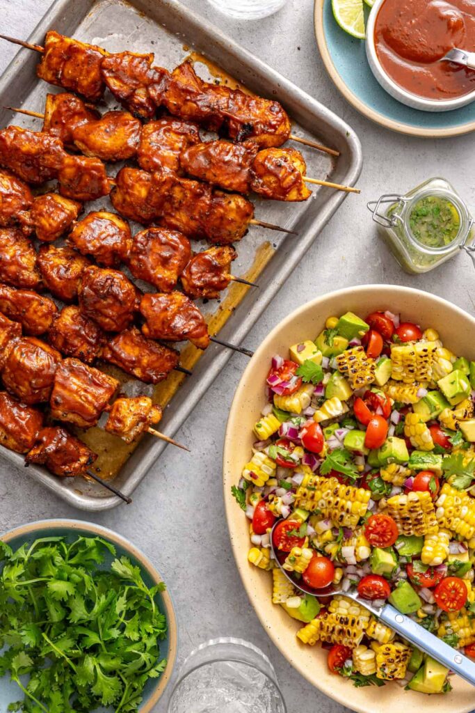 High-protein BBQ chicken skewers paired with fresh corn and tomato salad