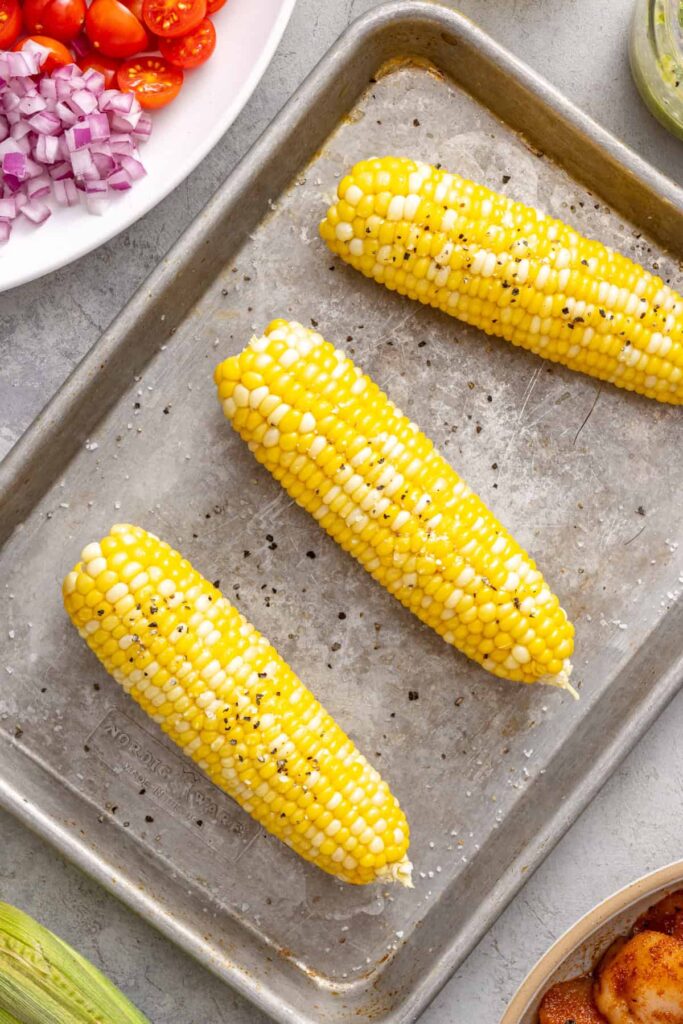 Fresh corn coated with olive oil before grilling for corn and tomato salad