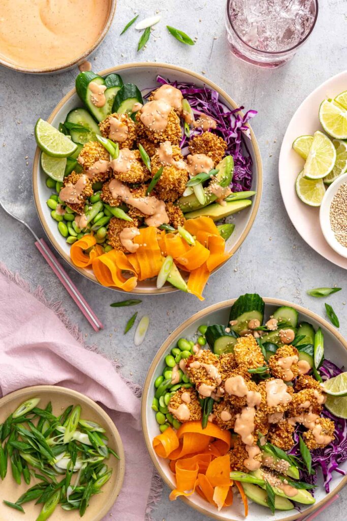 Overhead view of healthy air fryer bang bang shrimp bowls topped with a homemade, dairy-free bang bang sauce.