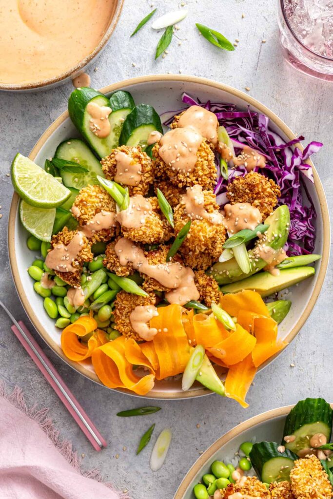 Bang bang shrimp rice bowls drizzled with creamy dairy-free sauce and finished with sesame seeds.
