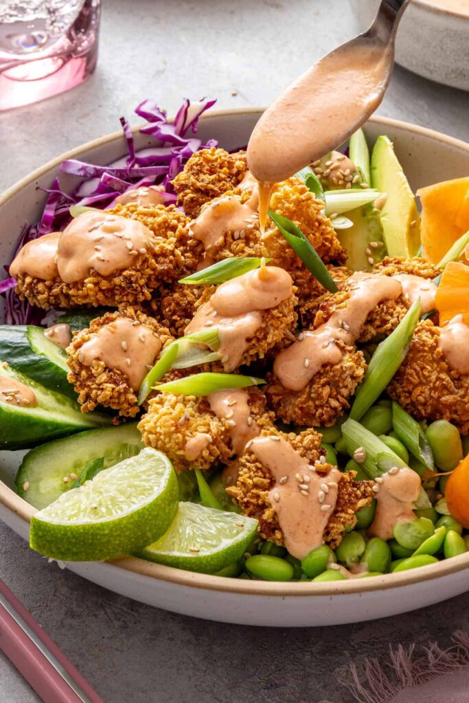 Fresh homemade bang bang sauce poured over healthy shrimp bowls.