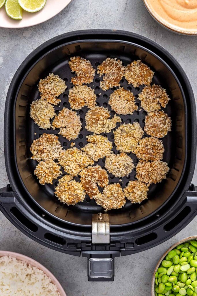 Breaded shrimp arranged in a single layer inside the air fryer basket before cooking