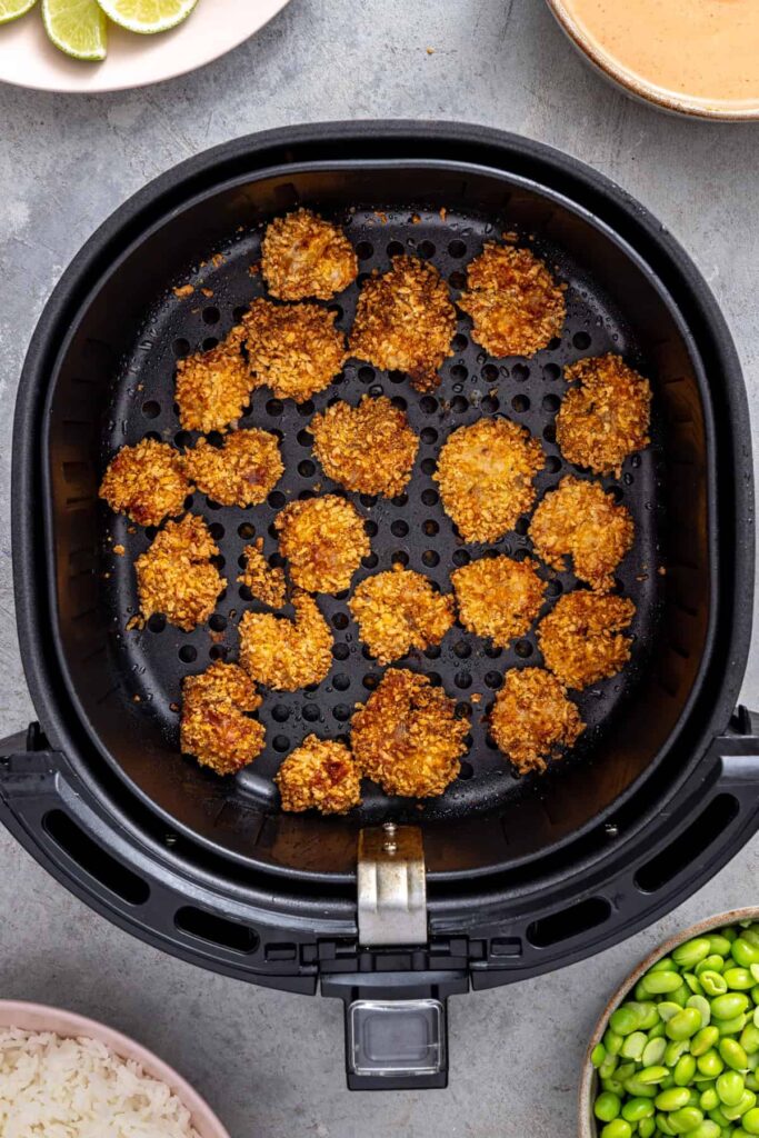 freshly cooked golden crispy shrimp resting in an air fryer basket