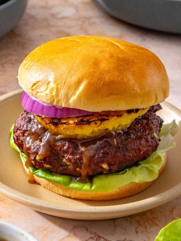 Juicy Hawaiian teriyaki burger with grilled pineapple, butter lettuce, red onion, and gluten-free brioche bun on a plate