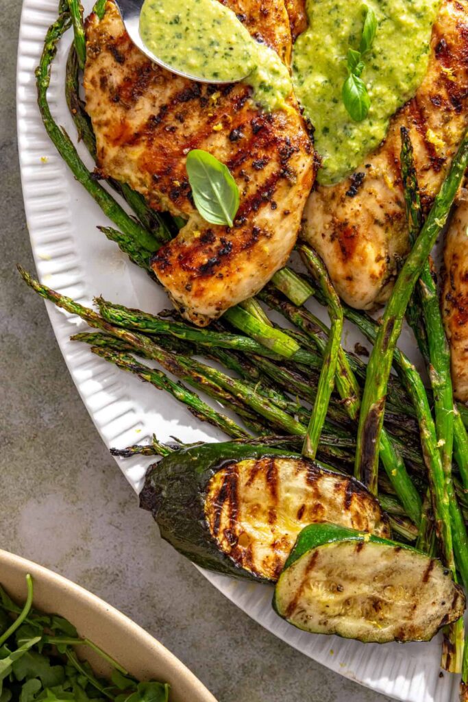 Colorful grilled vegetables served alongside lemon pesto chicken